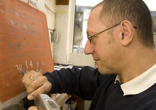 Photo:Close up of Glen hand carving an inscription on a headstone