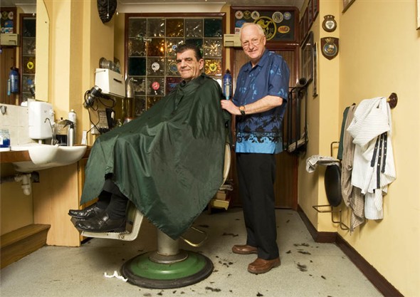 Photo:Portrait of Philip Jones, owner of PJ's cutting the hair of one of his regular customers Anthony Thomas