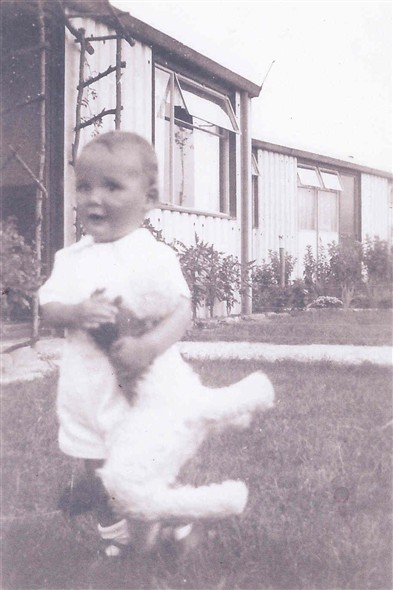 Photo:Photograph of a child outside a prefab on Shrublands Estate